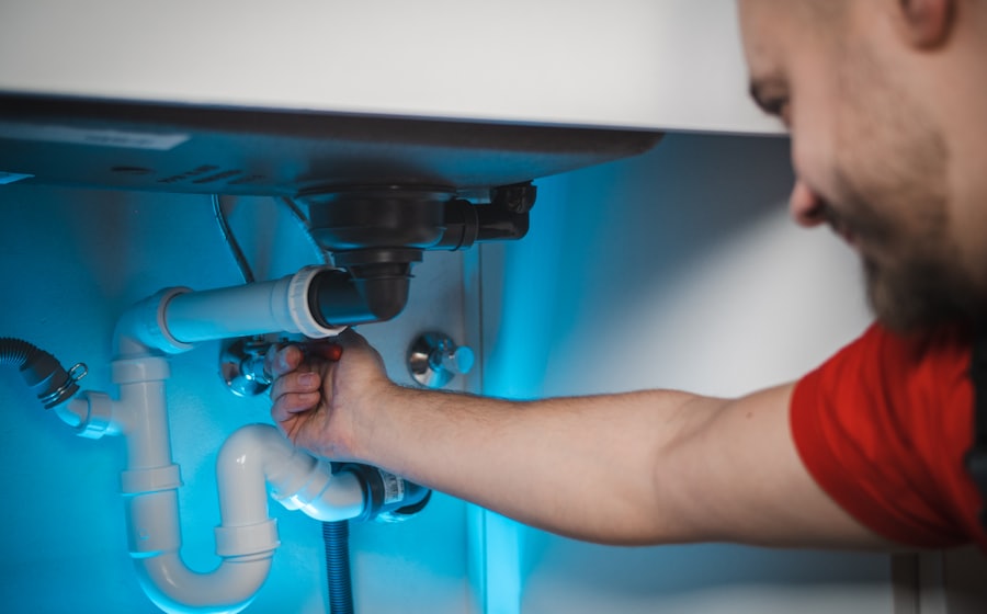 Plumber fixing pipes under a sink